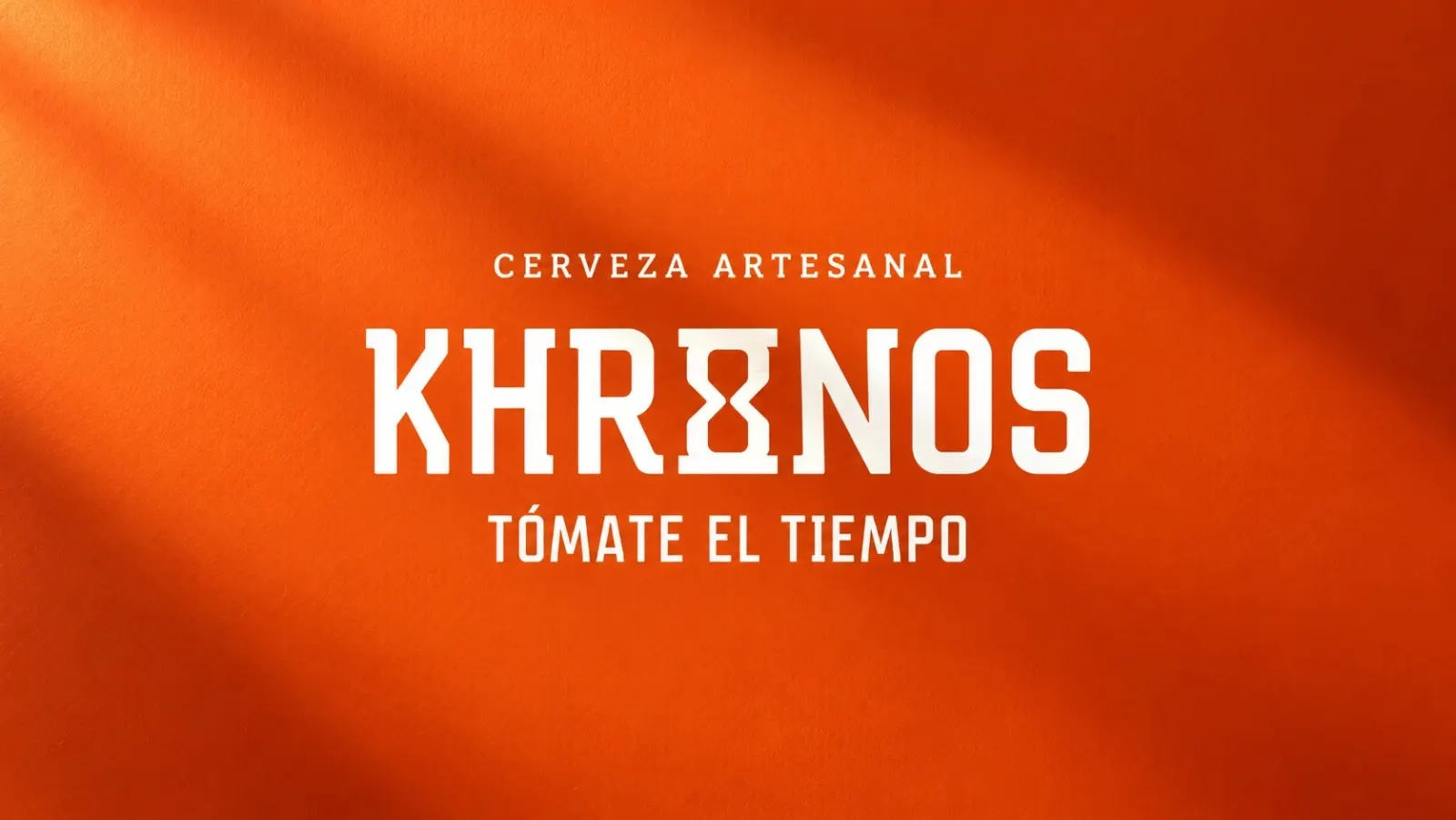 Logotipo de Cerveza Khronos con el tagline “Tómate el tiempo” en blanco sobre un muro naranja.